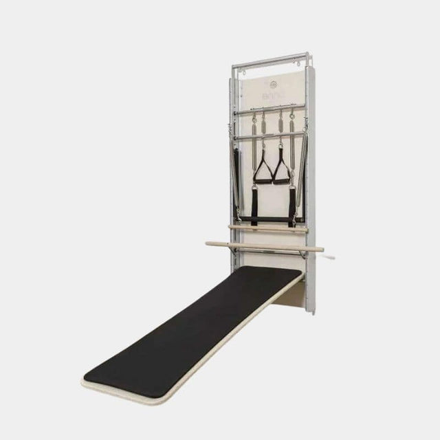 Pilates Wall Unit 5-en-1 isolée sur fond gris montrant tapis incliné noir déployé et finition aluminium brossé compacte